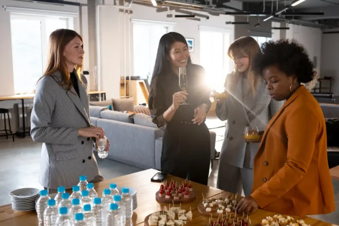 Mulheres se divertindo em uma reunião com comida e bebida, promovendo experiências de marca memoráveis em evento corporativo.